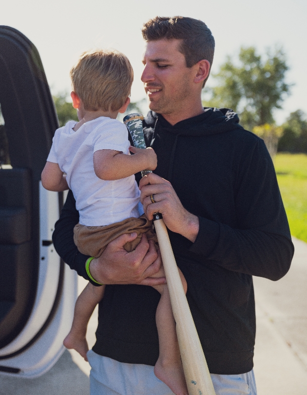 man holding a child and a baseball bat