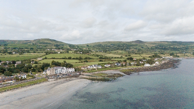 The sea meeting the beach with a white building on the shore